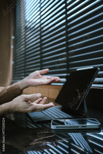 Close-up of a person using a smartphone while working on a laptop, multitasking with modern digital devices in a workspace.