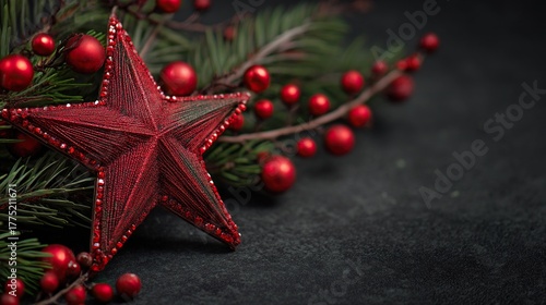 A close-up red Christmas star with green pine branches and red ornaments placed on a dark background, captured with a shallow depth of field to highlight the star and festive elements.