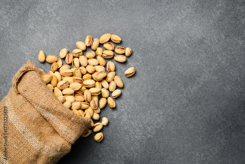 Linen bag with pistachios. Salted nuts. On a gray concrete background. Top view, free space for text.