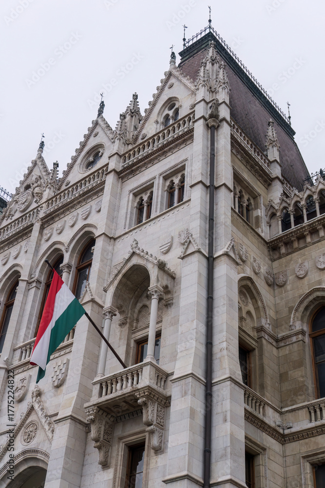 Fototapeta premium Flags on the beautiful old building of the Hungarian Parliament in neo-Gothic style