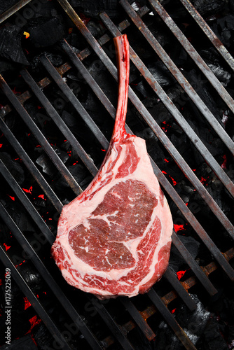 A raw aged Tomahawk steak is grilled over hot coals. Barbecue. Top view.