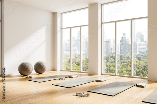 Foto Bright yoga studio interior design with large windows, scenic city view, exercise mats, dumbbells, and fitness balls on wooden floor