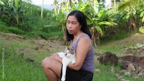 A sad young woman sitting while holding a cat on her lap. 