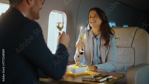 Two successful business partners celebrating a deal by clinking champagne glasses and dining together while traveling in a luxurious first-class cabin on a private airplane for a corporate trip