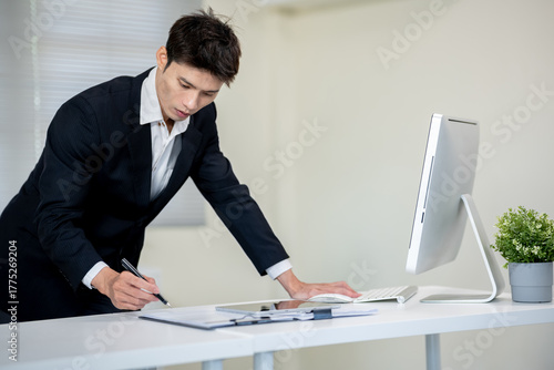 A businessman is discussing work with a client at a desk in an office.