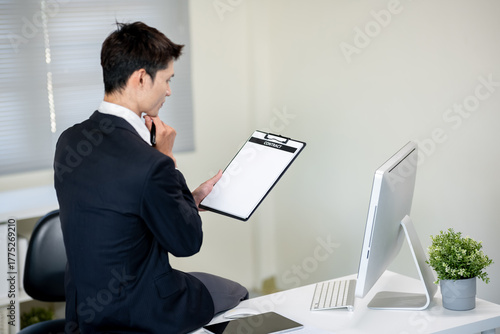 A businessman is discussing work with a client at a desk in an office.