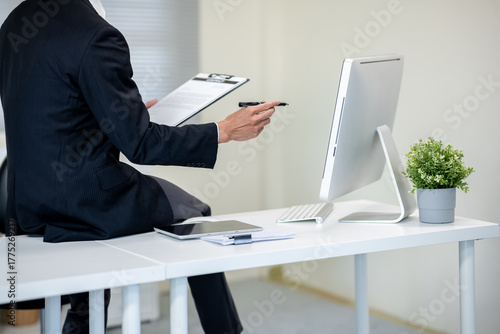 A businessman is discussing work with a client at a desk in an office.