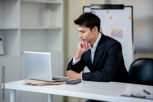 A businessman is discussing work with a client at a desk in an office.