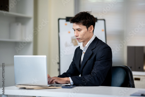 A businessman is discussing work with a client at a desk in an office.