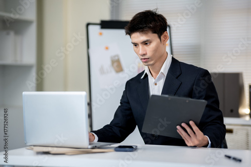 A businessman is discussing work with a client at a desk in an office.