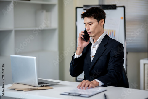 A businessman is discussing work with a client at a desk in an office.