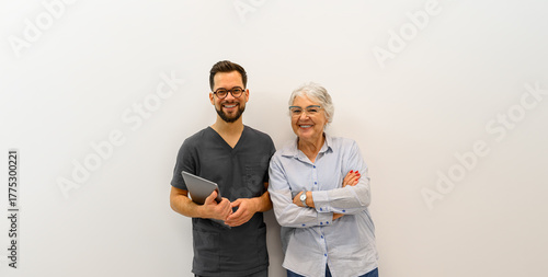 Portrait of smiling male ophthalmologist with senior patient standing together against white background