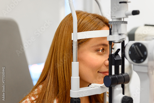 Close-up of female patient undergoing eye examination with slit lamp light focused on her eyeball at clinic