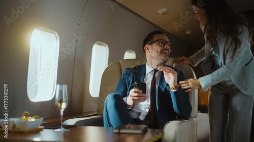 Two successful colleagues enjoying a comfortable flight in a private jet, laughing and interacting while looking at a smartphone, representing a luxurious business travel lifestyle