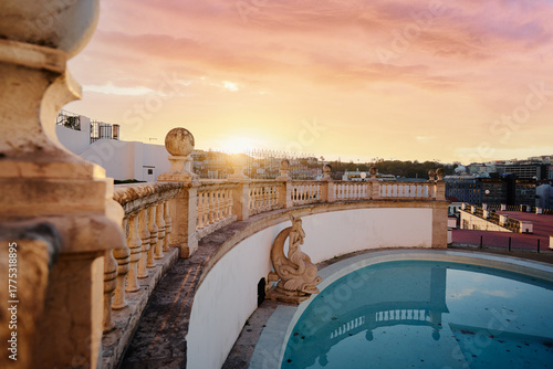 A park terrace with an empty pool and a cityscape view at sunset.