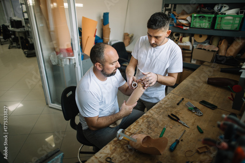 Two technicians collaborating on prosthetic arm in workshop