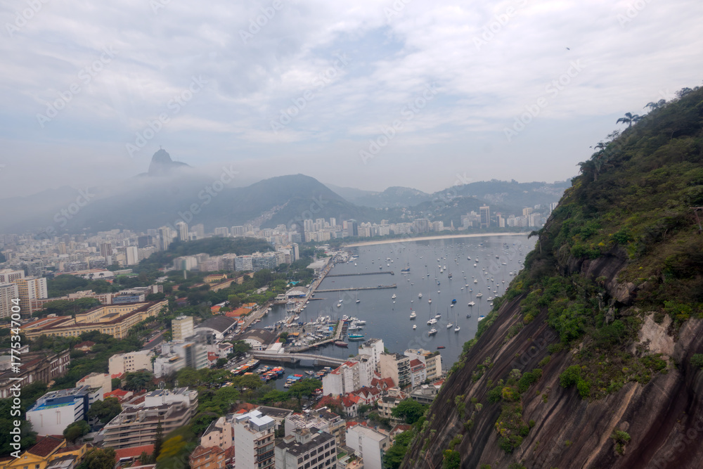 Obraz premium Aerial view from cable car at Urca Hill and Sugarloaf Mountain at Brazilian city of Rio on a cloudy spring day. Photo taken October 12th, 2025, Rio de Janeiro, Brazil.