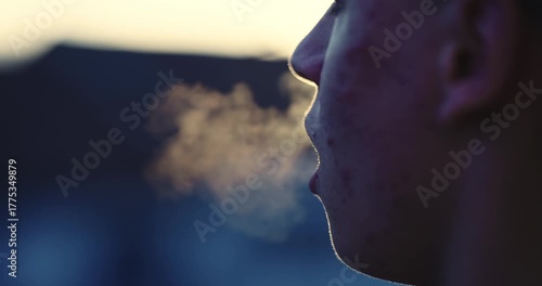 Young man with acne breathing hard after morning exercise backlit by sunrise sun, slow motion cinematic shot
