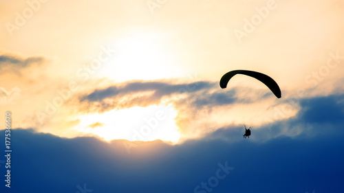 Paraglider soaring above clouds during sunset creates breathtaking view in evening sky