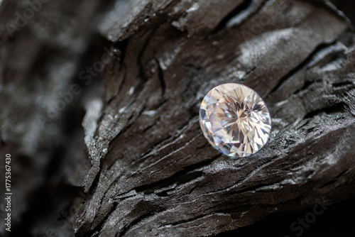 Macro shot of brilliant cut diamond placed on rough black stone texture. Perfect for luxury branding, jewelry design, gemstone background, product mockup, or gemology and editorial use.