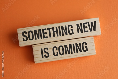 Something new is coming announcement on wooden blocks over orange background, launch teaser message.