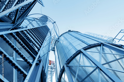 Foto Industrial silos under clear blue sky with steel infrastructure