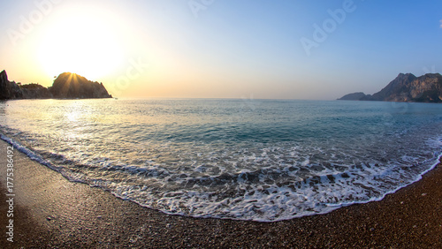 Fototapeta Naklejka Na Ścianę i Meble -  Golden sunrise over tranquil beach in Turkey with gentle waves and distant hills