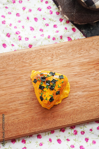 1 on 1 replica of japanese onigiri topped with mentai sauce and seaweed on wooden background