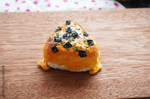 1 on 1 replica of japanese onigiri topped with mentai sauce and seaweed on wooden background