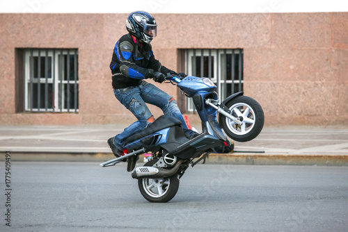 Biker balances on one wheel showcasing stunt skills on a city street