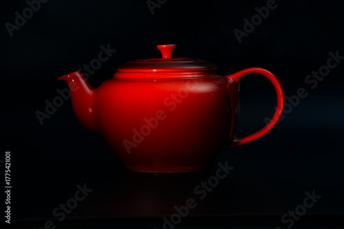 Red tea pot with black background. 