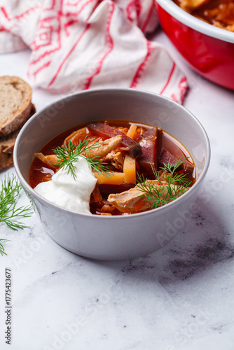 Classic homemade borscht with chicken in a grey bowl.