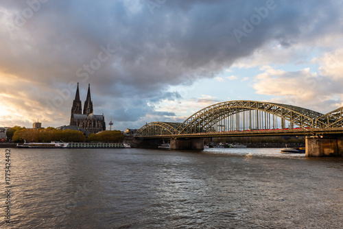 Cologne, Germany - October 26, 2025: Historic landmark of Cologne with the Hohenzollern Bridge in the foreground and the Gothic Cologne Cathedral in the background at sunset