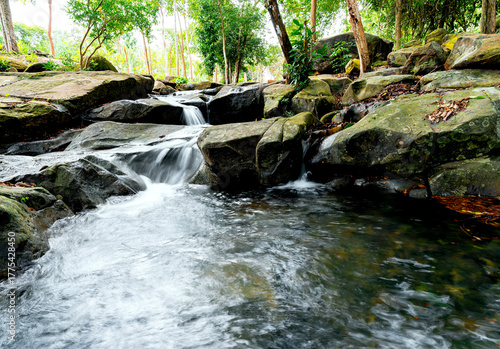 Small waterfall and pool are beautiful flowing through crevice in the rocks. Among forest with shade and in national park of Thailand.