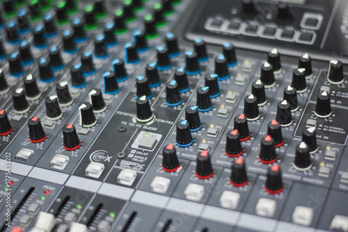 Close-up view of faders and knobs on an audio mixer.