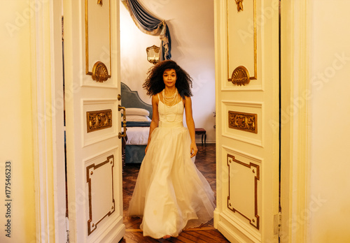 Photography Young African in white evening dress and jewelry comes out of decorated doors