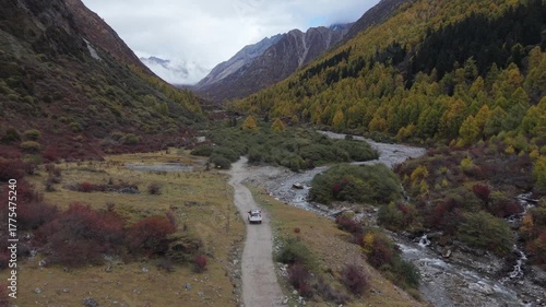 Aerial Tracking Drone Shot of Off-Road Vehicle Driving Through Autumn Mountain Valley Western Sichuan, China