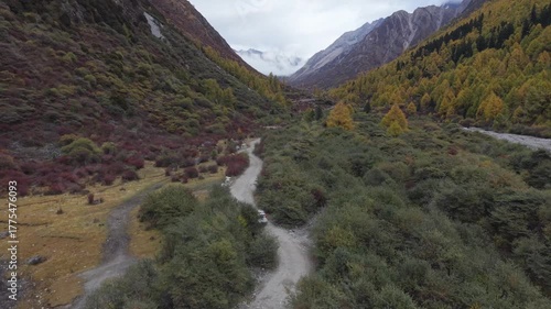 Aerial Tracking Drone Shot of Off-Road Vehicle Driving Through Autumn Mountain Valley Western Sichuan, China