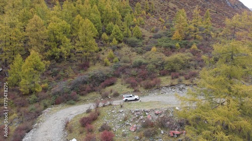 Aerial Tracking Drone Shot of Off-Road Vehicle Driving Through Autumn Mountain Valley Western Sichuan, China