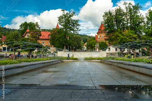 Main square and modern fountain in the Spa Park of Krynica Zdroj, Poland, surrounded by historic resort architecture.