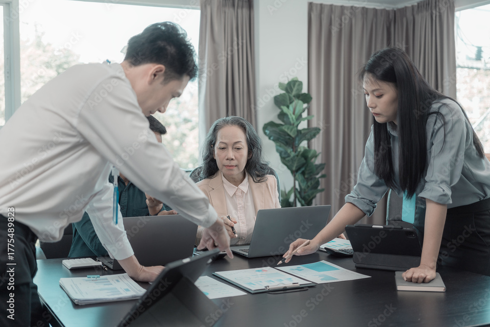 Fototapeta premium Group of business people discussing charts and graphs showing results of teamwork of colleagues working together at desks in office and discussing documents.