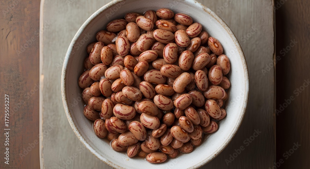 Fototapeta premium Dry pinto beans in a rustic bowl, top view on a dark wooden background with copy space. Raw, uncooked speckled legumes, a staple ingredient for healthy Mexican cuisine and high fiber diets