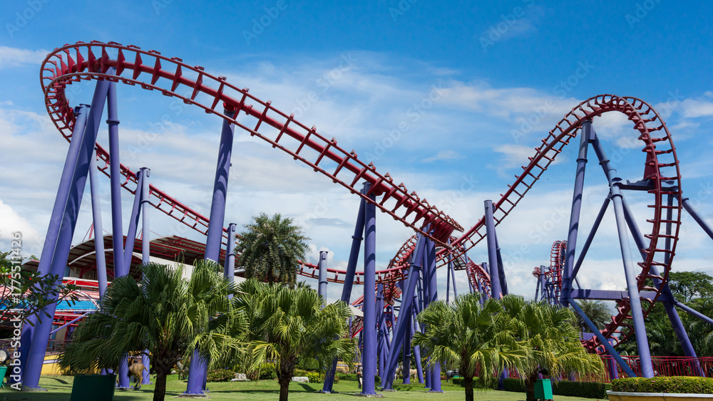 Fototapeta premium Colorful roller coaster in amusement park under bright sky, symbolizing fun, thrill, and excitement.