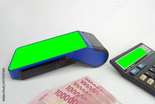 Electronic Data Capture (EDC) machines  with green screen and calculator with Indonesian money, finance technology concept
