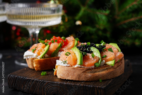 Avocado and salmon appetizer on the Christmas table. Canapes with fish and caviar. Top view