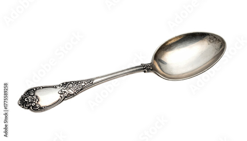 Ornate silverware teaspoon lays diagonally against a stark black background. Patina hints to age and use