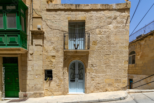 A typical house front in Birgu, Malta - with white door and green door, and a traditional green balcony