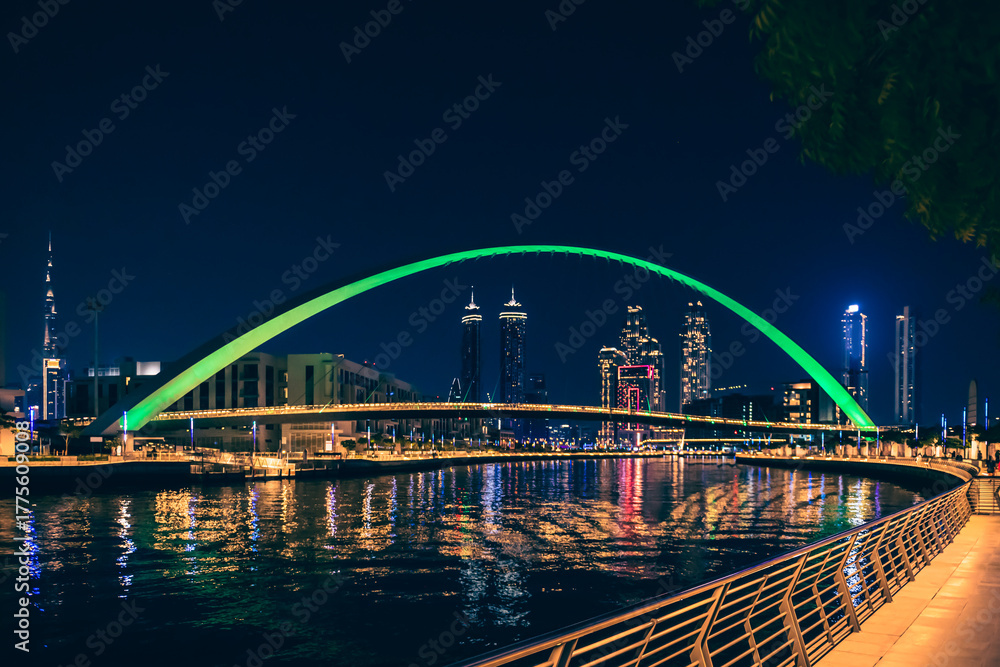 Obraz premium Dubai downtown night city skyline. Bridge over the canal. Modern skyscrapers and lights are reflected in the water.