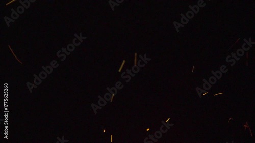 Flying sparks on black background — glowing metal particles in slow motion