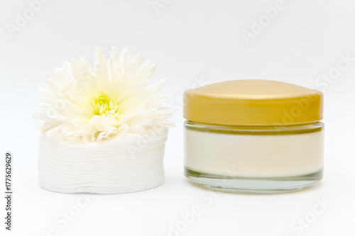 White glass container with white cotton pads flowers on white background.